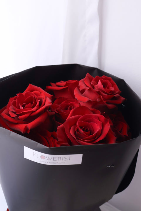Close-up of red roses inside black bouquet wrapping
