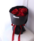 Angled view of a red rose bouquet in black wrapping