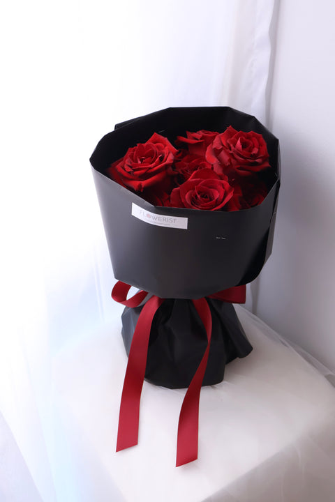 Angled view of a red rose bouquet in black wrapping