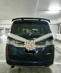 White floral wedding car arrangement with ivory ribbons on a dark van