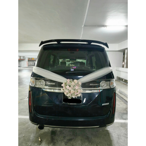 White floral wedding car arrangement with ivory ribbons on a dark van